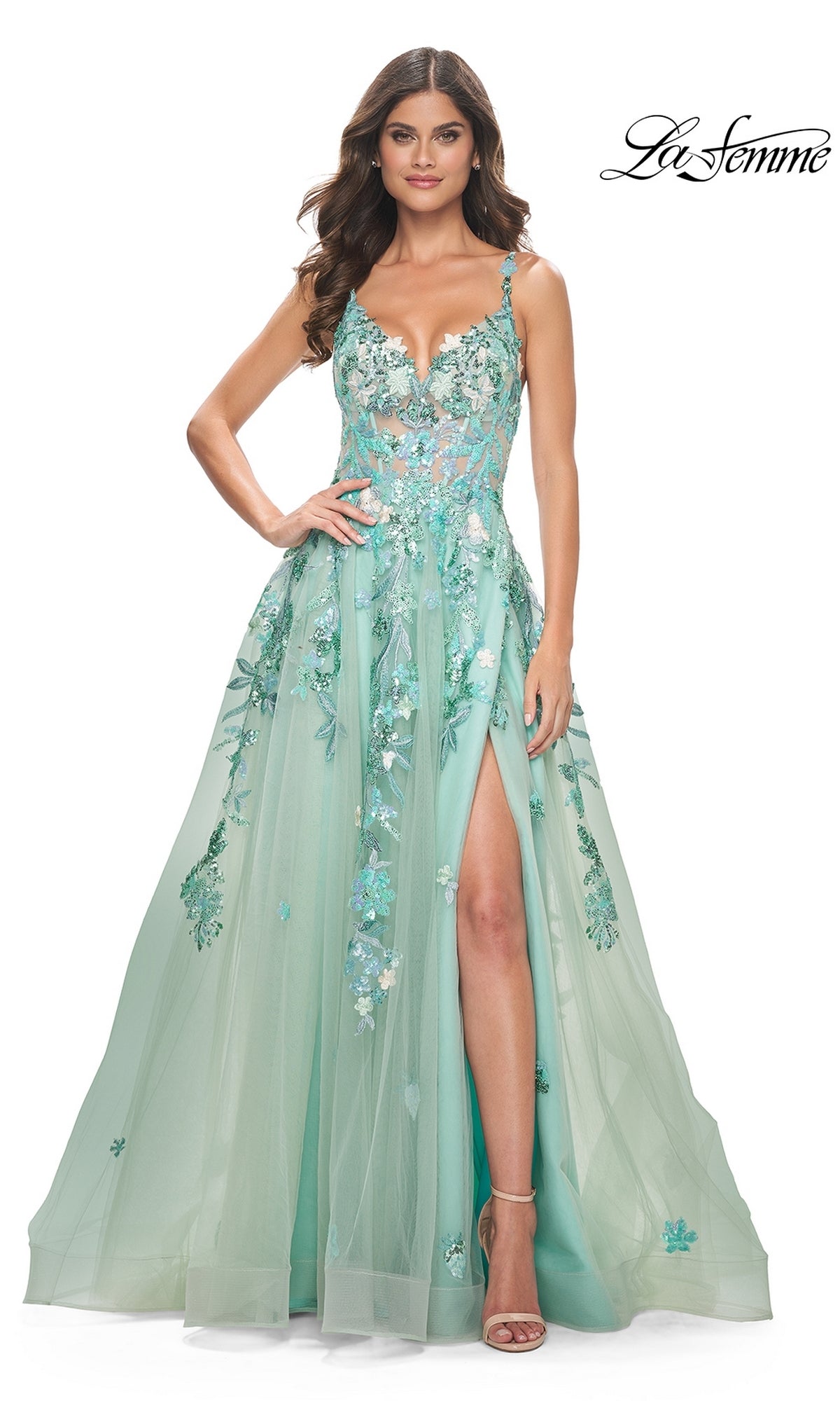 A woman wears the La Femme Sequin-Print Long Green Prom Dress 32347, featuring sequin floral embroidery, thin straps, a fitted bodice, and a high leg slit, posing with one hand on her hip.